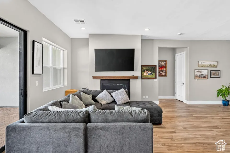 Recessed lighting, wood-finish flooring, a built-in fireplace with a wood mantle, a white trim interior door, and a sliding glass door