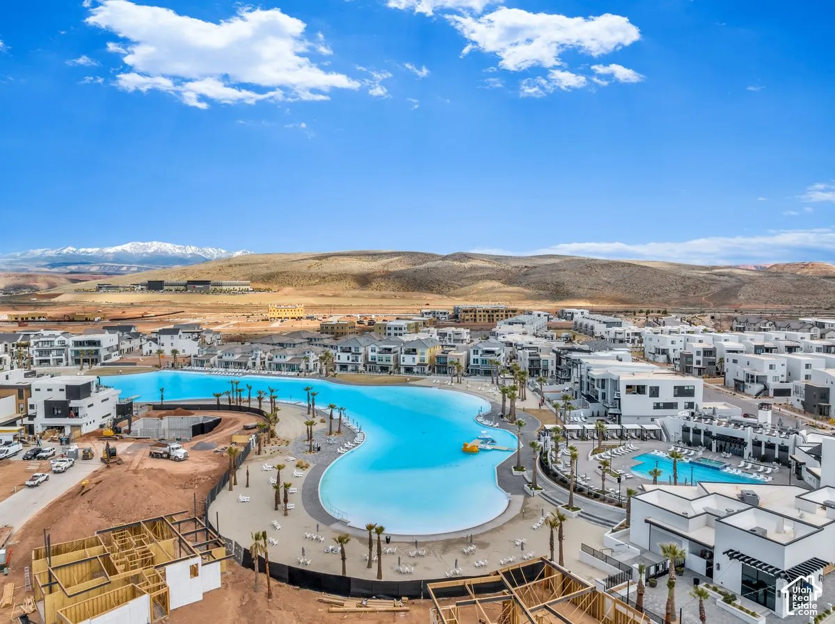 Expansive community featuring a large lagoon, surrounding residential structures, a separate swimming pool, and mountainous terrain in the background