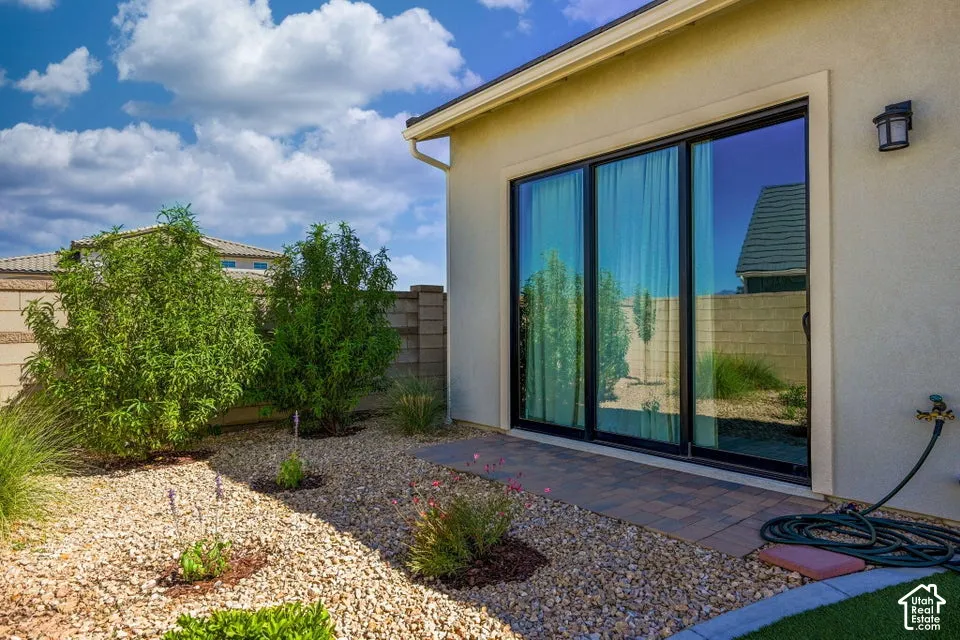 Sliding glass door system, paver patio, stucco exterior, gravel landscaping, and mature shrubbery