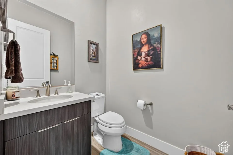 Powder room featuring a single vanity with a white countertop, an undermount sink, and a two-door wood-finish cabinet