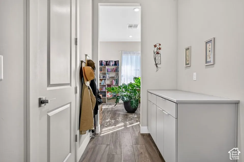 Hallway featuring wood-finish flooring, white paneled doors, and built-in white cabinetry with a light-toned countertop