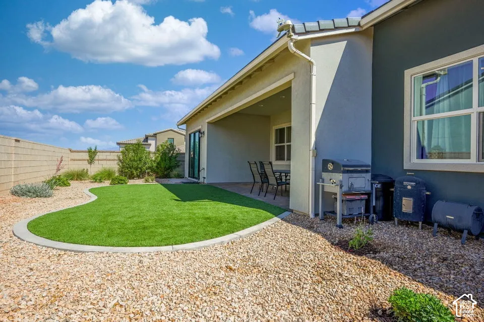 Backyard featuring a covered patio, artificial turf lawn, gravel landscaping, and a privacy block wall