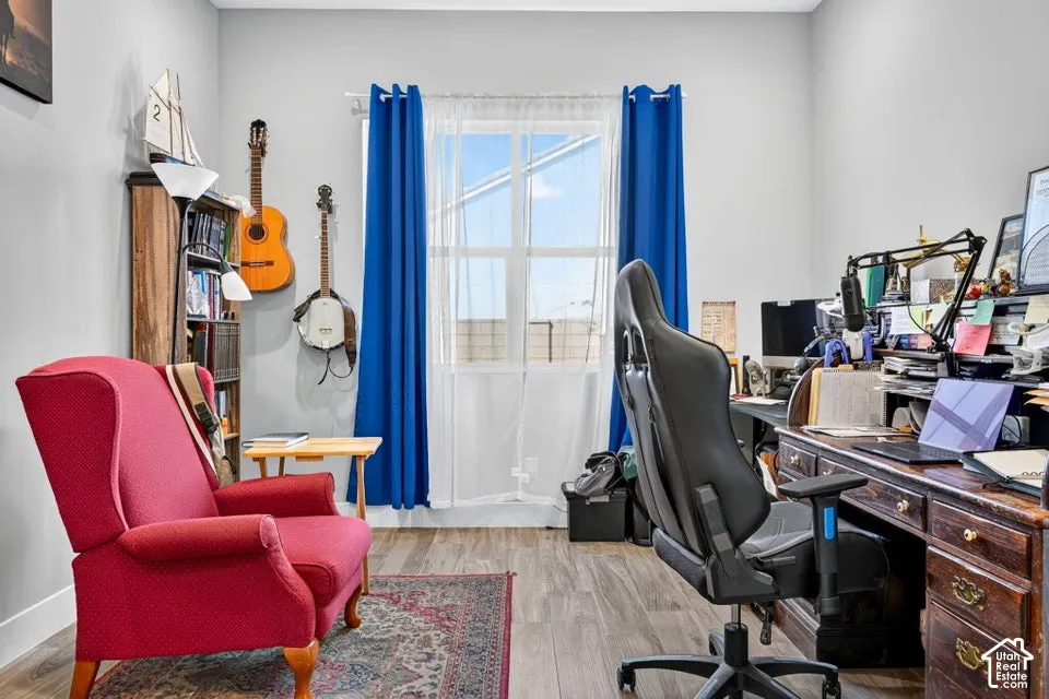 Wood-finish flooring, light grey walls, and a large window with white sheers