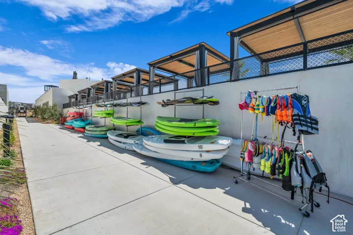 Paved walkway featuring multiple watercraft storage racks and an array of life vests