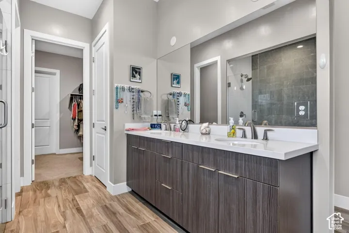 Wood-finish flooring leading to a dual vanity with a white countertop and undermount sinks