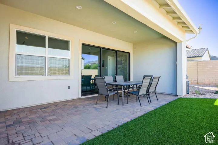 Covered patio with paver flooring, recessed lighting, sliding glass door access, and artificial turf
