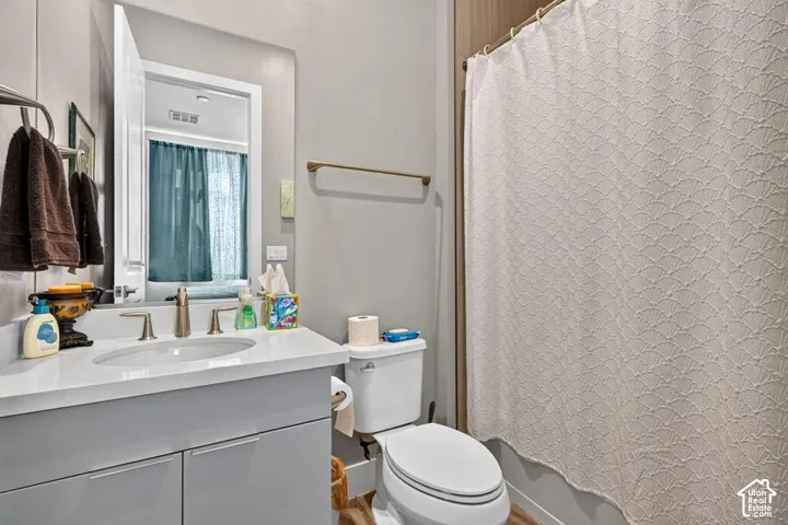 Vanity with undermount sink and brushed nickel faucet, large mirror, and toilet with wood-finish flooring