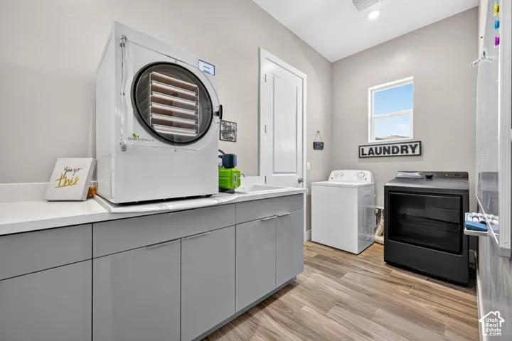 Laundry room featuring wood-finish flooring, white countertops, gray cabinetry, and a window