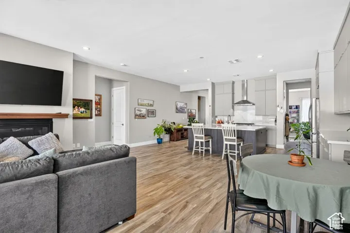 Recessed lighting, wood-finish flooring, fireplace with wood mantel, kitchen island with seating, and stainless steel range hood