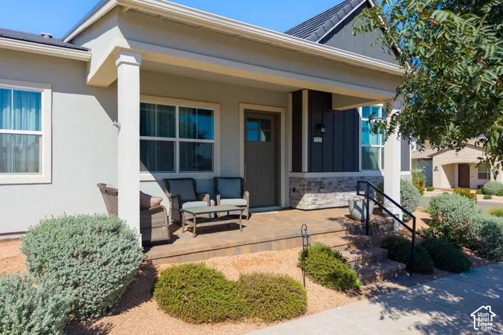 Covered front entry featuring a paver stone patio, decorative stone accents, and a dark wood-finish door