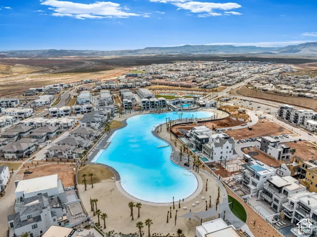 Expansive community featuring a large, blue-hued lagoon with sandy shores, surrounded by multiple residential structures