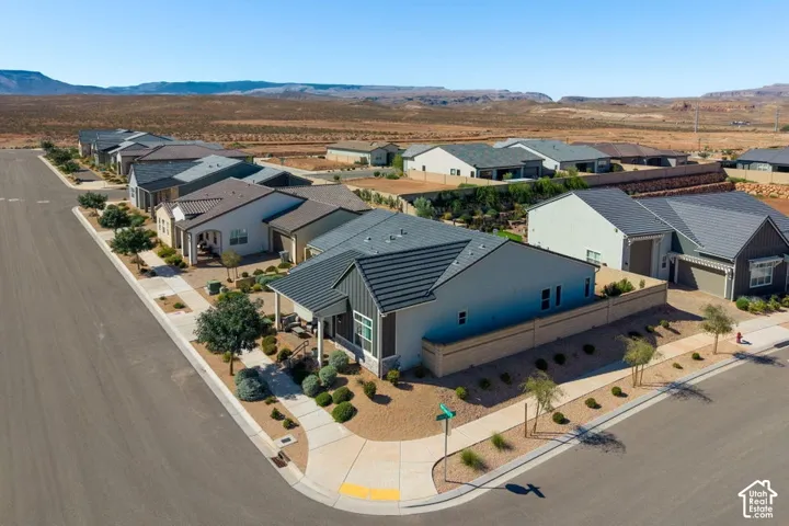 Corner lot property featuring a covered front porch, a two-car garage, and a low-maintenance xeriscaped front yard