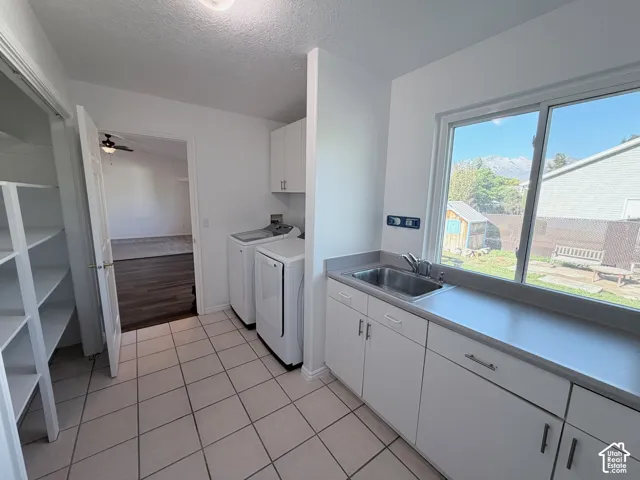 White tile flooring, built-in shelving, white cabinetry, integrated sink, and a large window