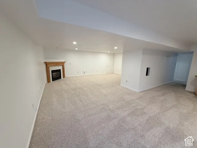 Spacious carpeted room featuring a built-in fireplace with a wood mantle and recessed lighting