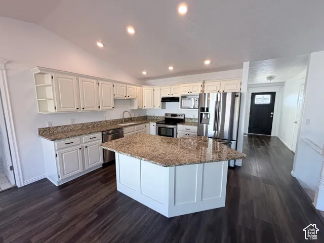 Kitchen featuring white cabinetry, granite countertops, stainless steel appliances, a center island, and LVP flooring