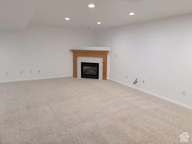 Expansive room featuring recessed lighting, a built-in fireplace with a stone surround, a wood mantel, and light-toned carpeting
