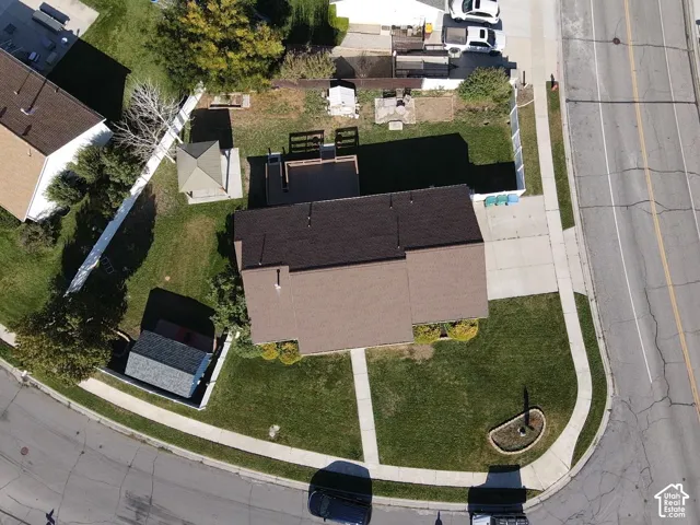 Expansive corner lot featuring a manicured lawn, paved driveway, and concrete walkways