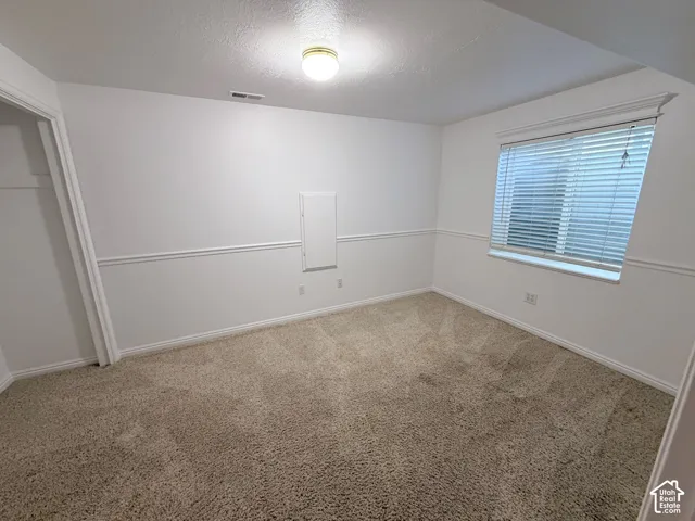 Carpeted room featuring a window with blinds, baseboard trim, and chair rail molding