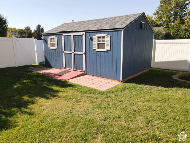 Blue storage shed with white trim, double doors, and two windows with shutters