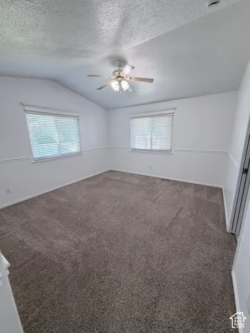 Vaulted ceilings with a ceiling fan, dual windows with blinds, and neutral carpeting