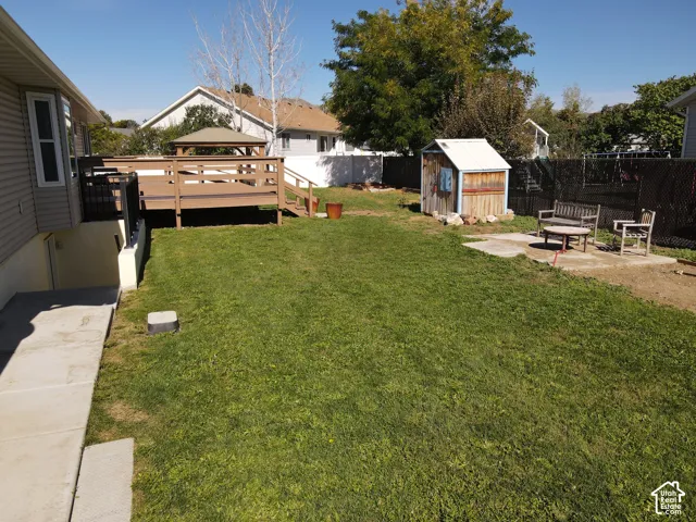 Expansive backyard featuring a large elevated deck with a built-in gazebo, a separate patio area, a concrete path, and a storage shed