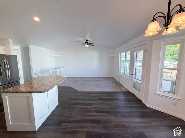 LVP flooring, vaulted ceilings, and a kitchen island with a stone countertop