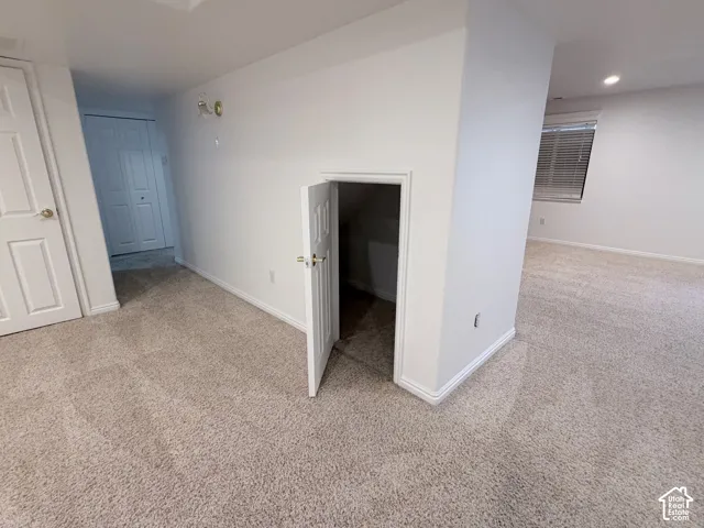 Neutral tone carpeting, white painted walls, recessed lighting, white doors, and a window with blinds