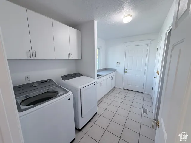 White cabinetry, tile flooring, built-in sink, and a solid exterior door