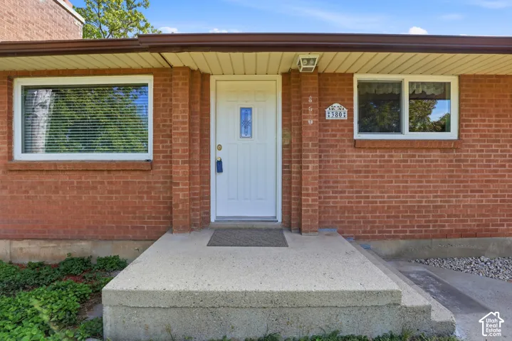 Brick exterior with white-framed windows, a white entry door with decorative glass, and a concrete entry porch