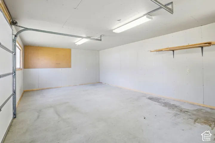 Concrete flooring, overhead fluorescent lighting, built-in wall shelving, and a window