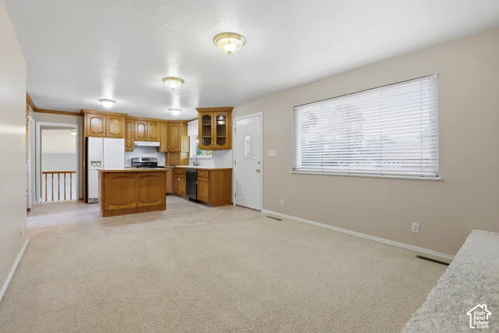 Kitchen with wood cabinetry, a central island, and white appliances