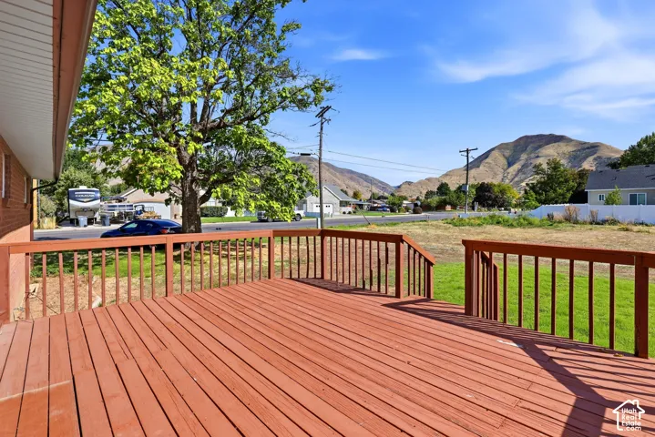 Expansive outdoor deck with wood railing, offering broad mountain scenery and a mature shade tree