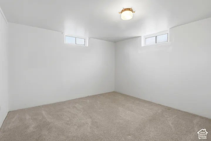 Recessed windows with natural light, light-toned carpeting, and a flush-mount ceiling light fixture