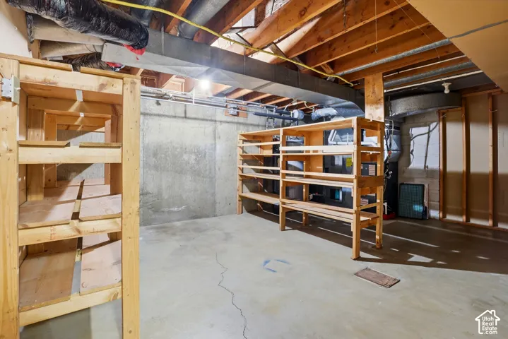 Unfinished basement with exposed ceiling joists and concrete flooring