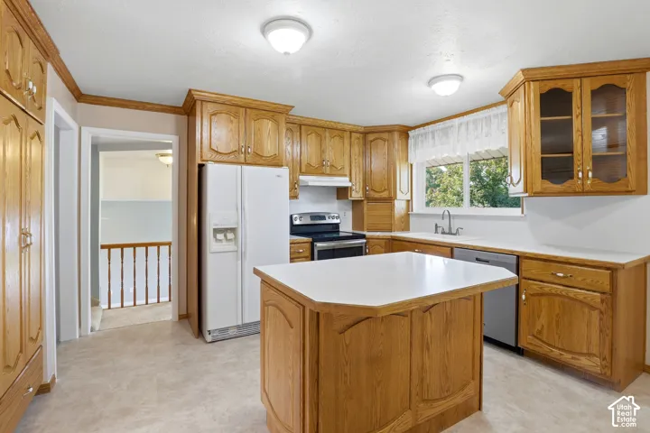 Kitchen featuring natural wood cabinetry, white countertops, a center island, stainless steel dishwasher, and a window