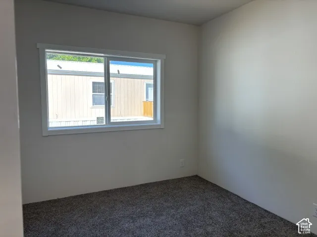 Carpeted flooring, white painted walls, and a sliding window with white trim