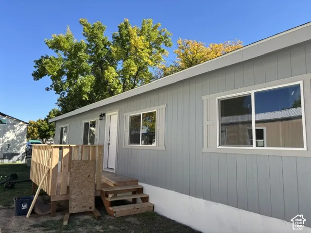 Light gray vertical siding exterior with white window trim and a partial wood deck