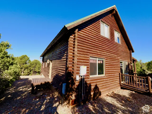 Log cabin exterior featuring a gable roof, wood siding, and multiple windows