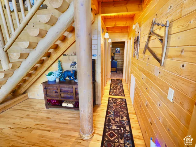 Hardwood flooring, natural wood paneling, wood-finished staircase, recessed hallway lighting, built-in wooden column