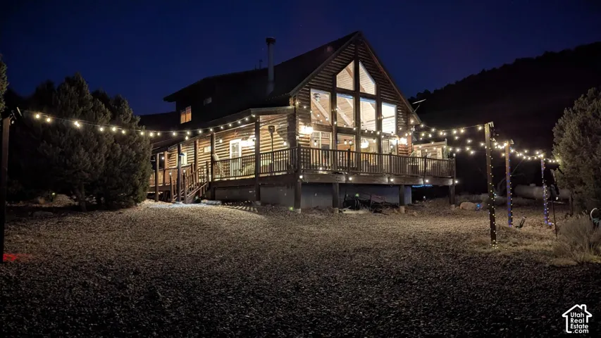 Log cabin exterior with a multi-level deck, expansive window design, and a wraparound covered porch