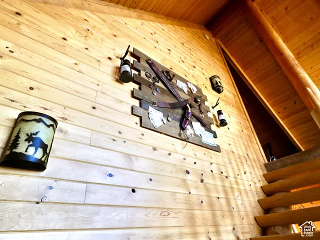 Wood-paneled wall, vaulted wood-paneled ceiling, exposed wood beams, wood stair treads, and mounted light fixtures