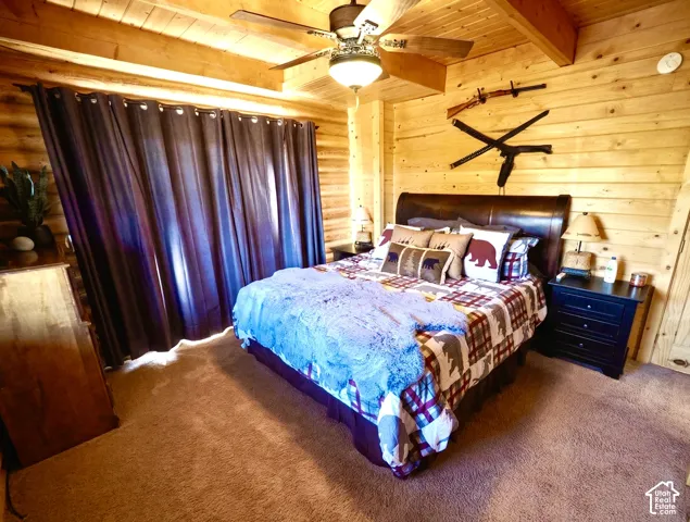 Vaulted wood-paneled ceiling with exposed beams, wood-plank walls, ceiling fan with integrated lighting, and carpeted flooring