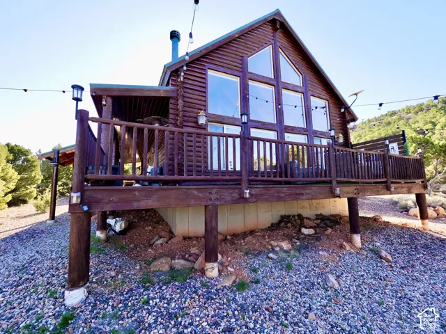 Log cabin exterior with a full-width elevated deck featuring a railing system