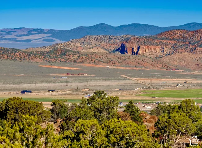 Expansive desert landscape with distant mountains, vibrant green fields, and scattered residential properties