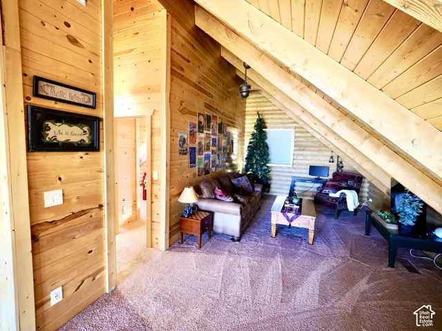 Vaulted wood-paneled ceilings with exposed beams, wood-plank walls, and plush carpeting