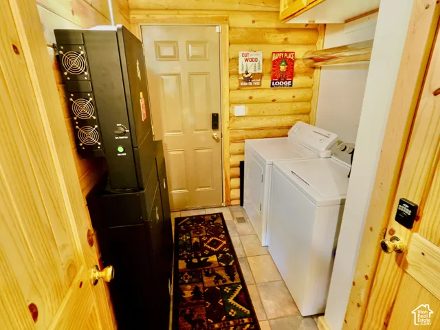 Log-style interior walls, tiled flooring, wood paneling, and a white washer and dryer set