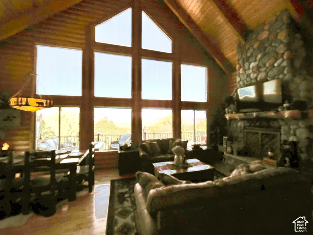 Vaulted wood-finish ceilings, an expansive stone fireplace, and a full wall of multi-pane windows