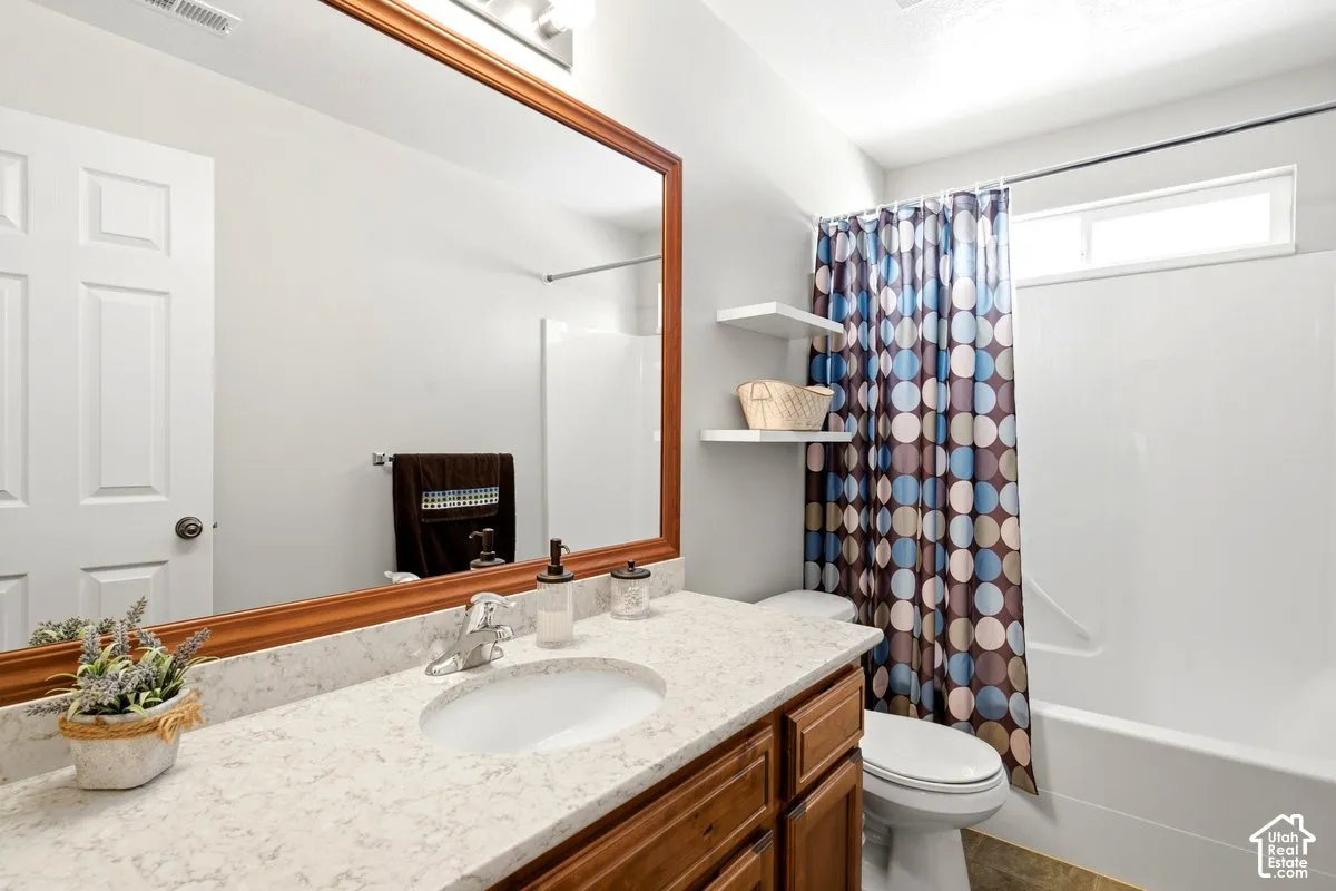 Bathroom featuring a wood-framed mirror, light-toned countertop, integrated sink, wood-finish cabinetry, and a shower-tub combination