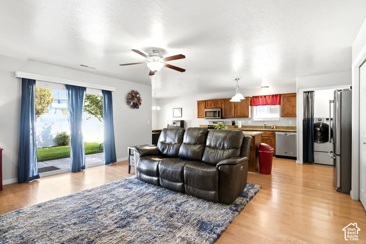 Sliding glass door leading to the backyard patio, wood-finish flooring, ceiling fan, wood cabinetry, and stainless steel appliances