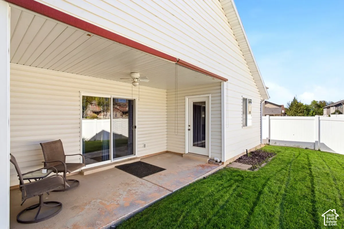 Covered patio with a ceiling fan, sliding glass door, and a privacy fence